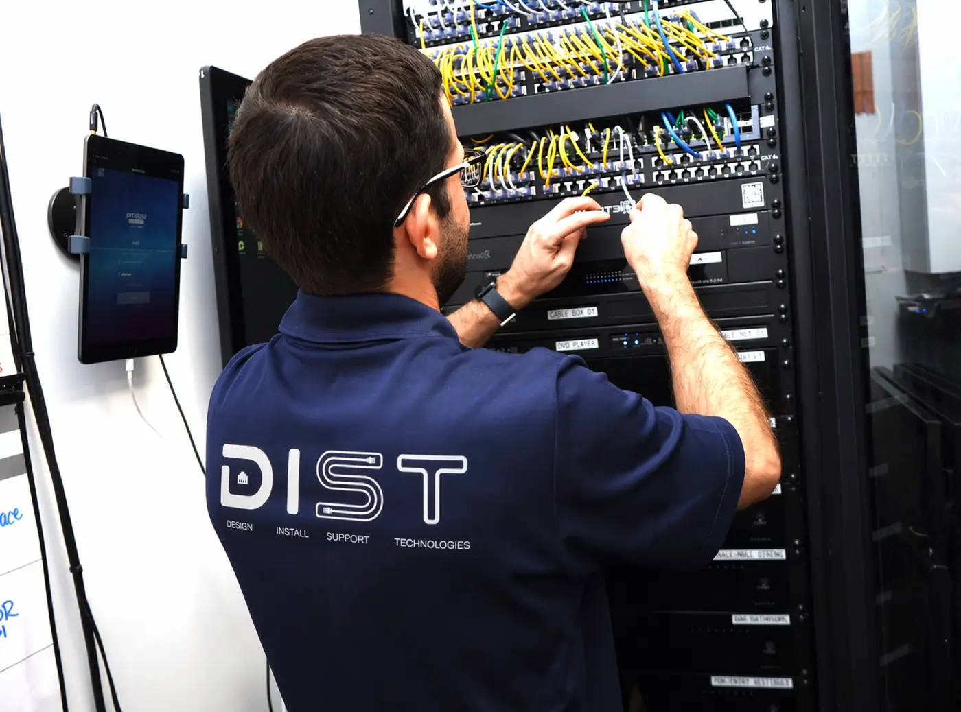 DIST technician in a branded shirt servicing a network rack