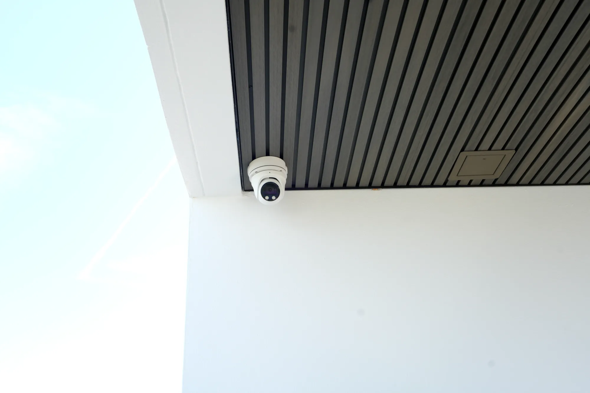 Exterior dome camera installed under a slatted soffit