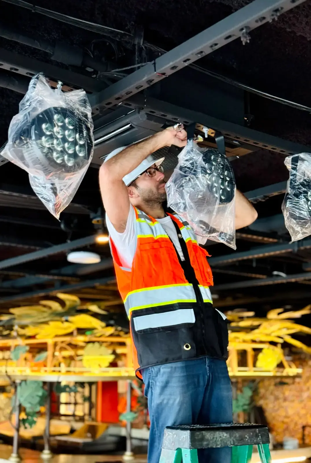 DIST installer rigging equipment in a venue ceiling