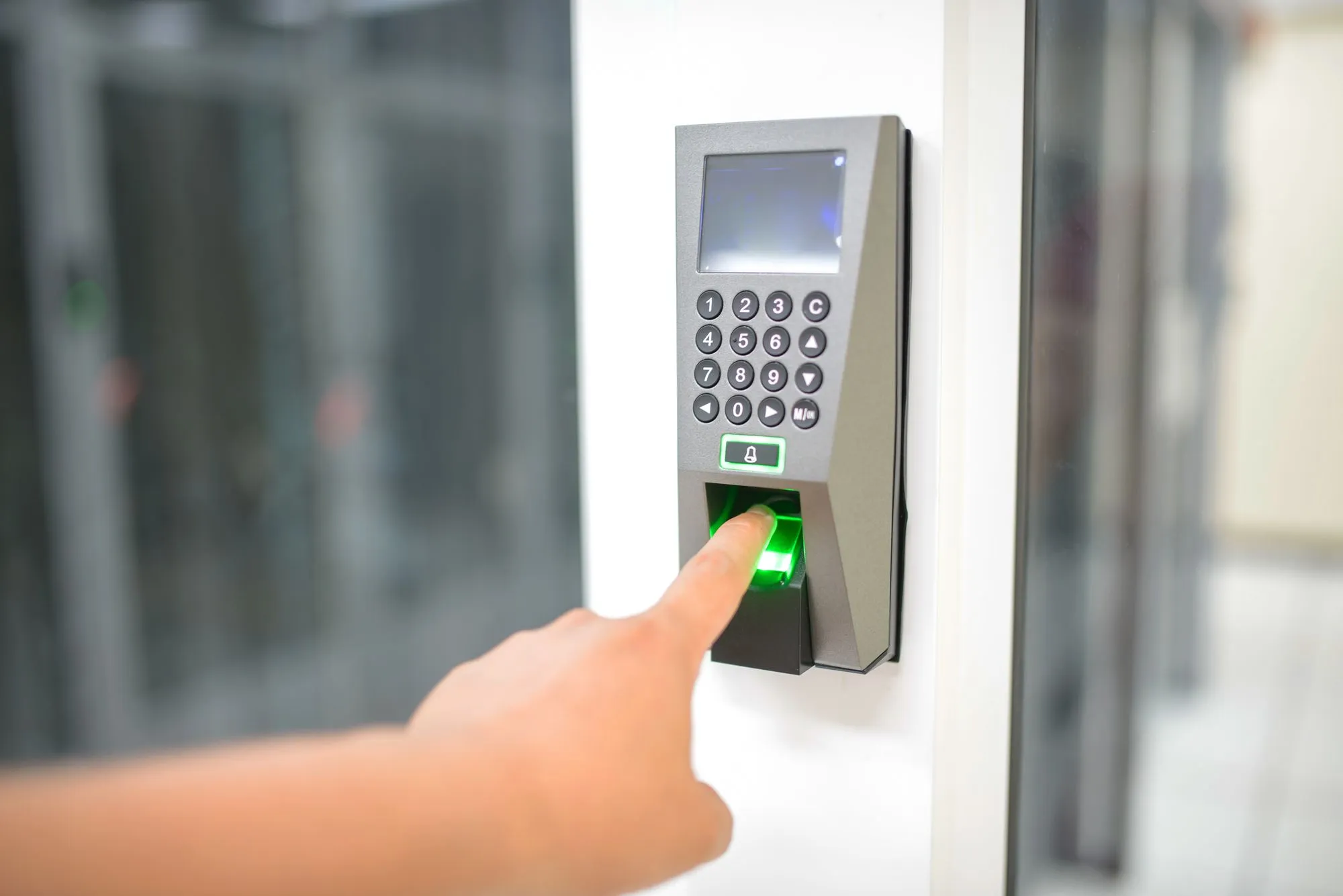 Finger on a fingerprint reader beside an office door
