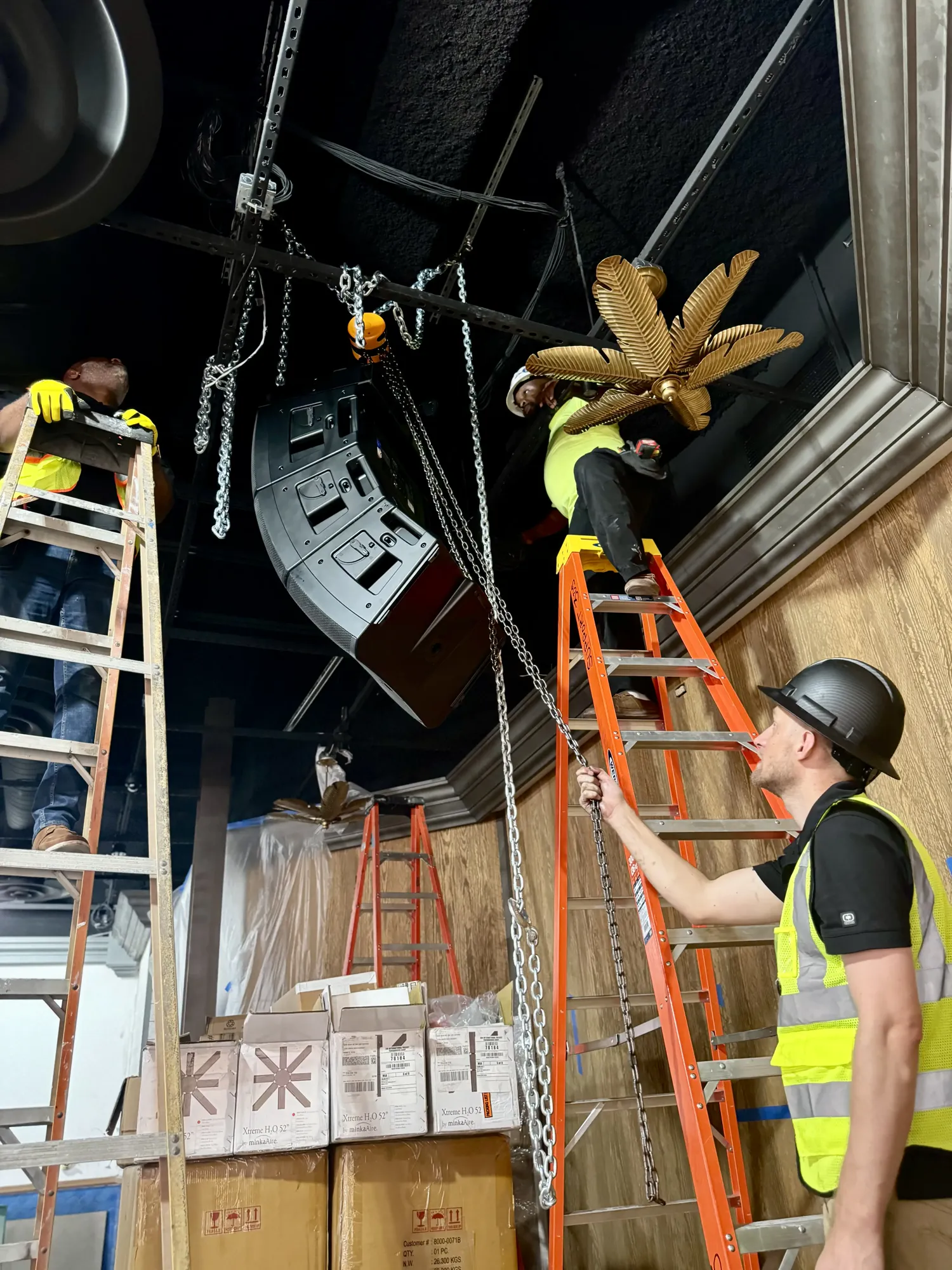 DIST crew rigging speakers and fixtures in a restaurant ceiling